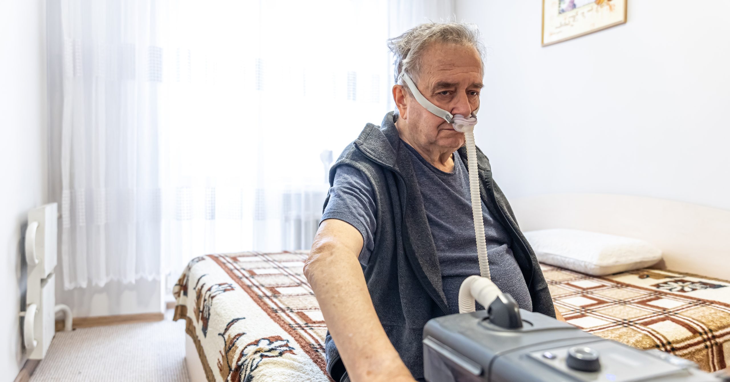 Elderly man using machine for old people who have problem with lungs.